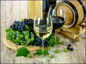 Winogrona obok kieliszków i beczki z winem