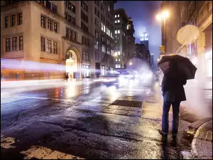 Mężczyzna pod parasolem na oświetlonej ulicy