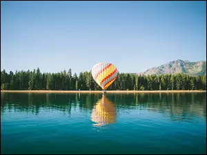 Przelot balonem nad jeziorem z widokiem na góry i las