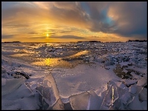 Zachodzące słońce nad morzem pokrytym bryłami lodu