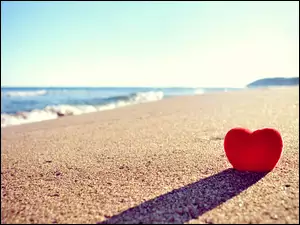 Czerwone serce wbite w piasek na plaży