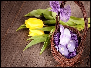 Wielkanocna kompozycja z pisanek w koszyczku i żółtymi tulipanami