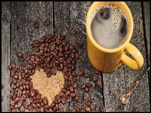 Kawa w kubki obok serca ułożonego z ziaren kawy