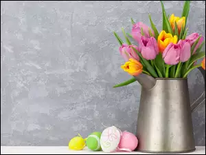 Wielkanocna kompozycja bukietu tulipanów w dzbanku z pisankami obok