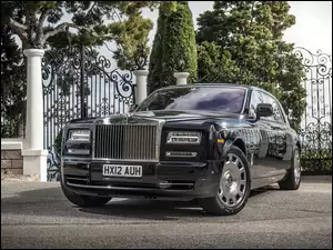 Samochód Rolls-Royce Phantom stoi na placu przed bramą