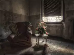 Bukiet róż na stoliku ze zniszczonym fotelem w opuszczonym wnętrzu