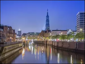 Kanał i oświetlony most w Hamburgu z widokiem na kościół sw Katarzyny
