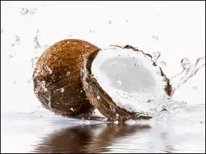 Połówka kokosa i cały w rozbryzgującej wodzie