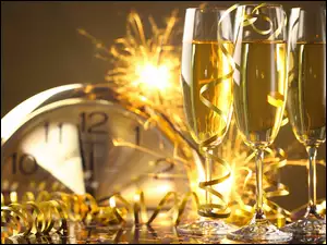 Kieliszki szampana i zegar odmierzający czas do Nowego Roku w rozmyciu