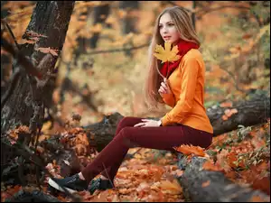 Jesienny las i dziewczyna siedząca na drzewie