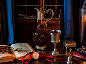 Kompozycja z karafką wina i książkami na oknie w świetle lampionów