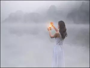 Kobieta z lampą we mgle