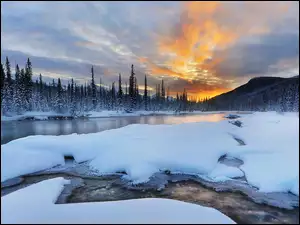 Rzeka w zimowym krajobrazie z lasem i górami