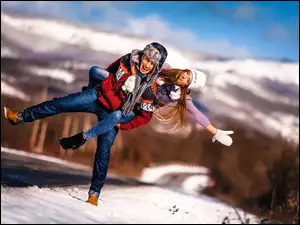 Radosna dziewczyna z chłopakiem na zaśnieżonej drodze w górach