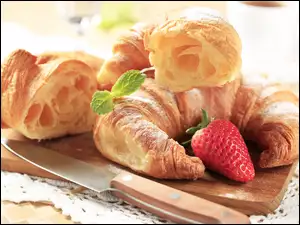 Francuskie rogaliki croissanty udekorowane truskawką na desce