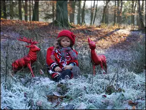Dziewczynka z figurkami jelonków na oszronionej leśnej polanie