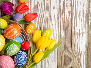 Wielkanocna kompozycja z pisanek w koszyczku i kolorowych tulipanów