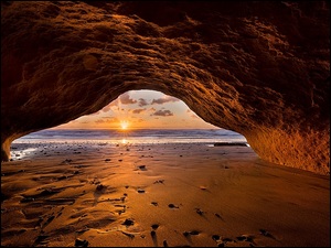Widok na zachód słońca z jaskini w skale nad morzem