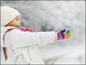 Dziewczynka wyciąga ręce do spadających płatków śniegu