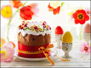 Wielkanocna lukrowana babka z jajkami i kwiatami na stole