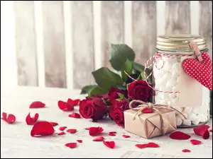 Walentynkowa kompozycja czerwonych róż z prezentem i słoikiem