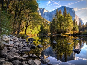 Park Narodowy Yosemite w Kaliforni z kamienistym brzegiem rzeki i widokiem na góry