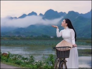 Azjatycka kobieta z rowerem nad rzeką