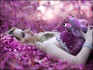 Kobieta w fioletowej sukience leży na kwiatach