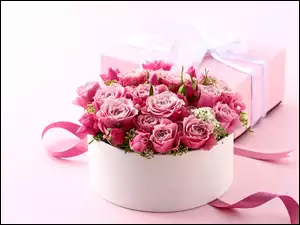 Bukiet róż w pudełku obok prezentu