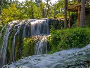 Wodospad wpadający do rzeki pośród zieleni