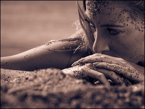 Leżąca kobieta z twarzą w piasku