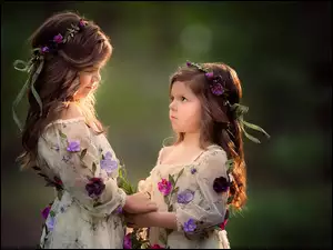 Dwie dziewczynki w kwiecistych sukniach i wiankach na głowie