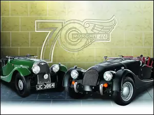 Dwa samochody Morgan 4/4 przy ścianie z logo