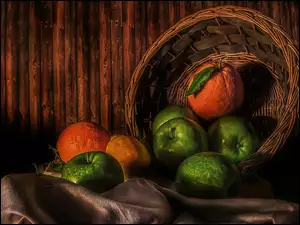 Jabłka i pomarańcze wypadające z kosza