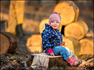 Dziecko siedzi na pniu ściętego drzewa