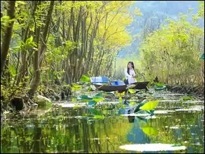 Dziewczyna w łódce na rzece porośniętej roślinnością