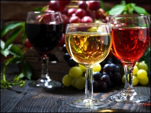 Winogrona obok kieliszków z kolorowym winem