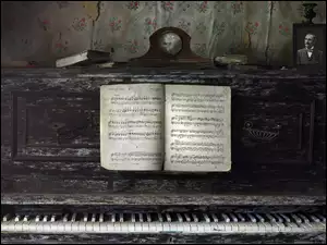 Zegar i fotografia położone na starym pianinie z nutami