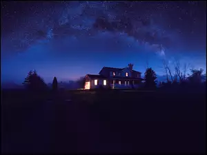 Gwieździste niebo nad oświetlonym domem