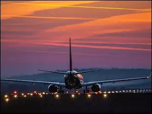 Lądujący o zachodzie słońca samolot pasażerski