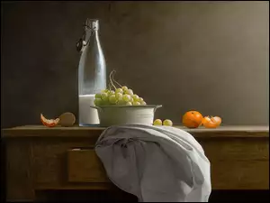 Miska winogron obok butelki z mlekiem na stole