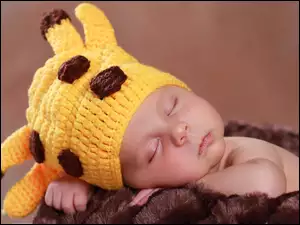 śpiące dziecko z żółtą czapeczką na futrzaku