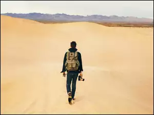 Mężczyzna z plecakiem i aparatem na pustyni