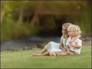 Dziewczynka obejmuje chłopca na trawie