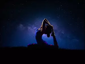 Ćwicząca jogę kobieta w pozycji gołębia na tle gwiazd
