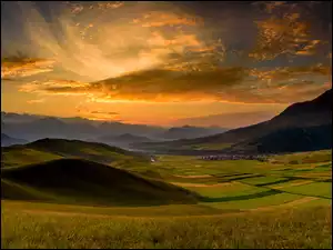 Zachód słońca nad polami i wzgórzami