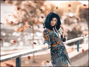 Dziewczyna z warkoczami i płaszczu z kapturem w jesiennej scenerii