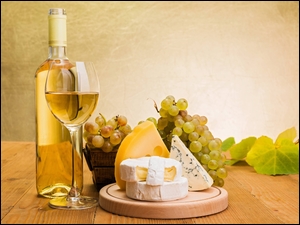 Sery na desce obok kiści winogron i wina w butelce i kieliszku