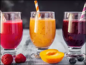 trzy pucharki z owocowymi koktajlami i kolorowymi słomkami