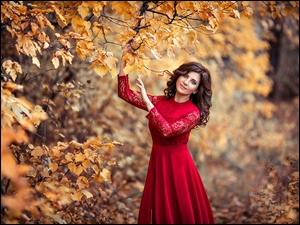 Dziewczyna w czerwonej sukience pozuje w parku